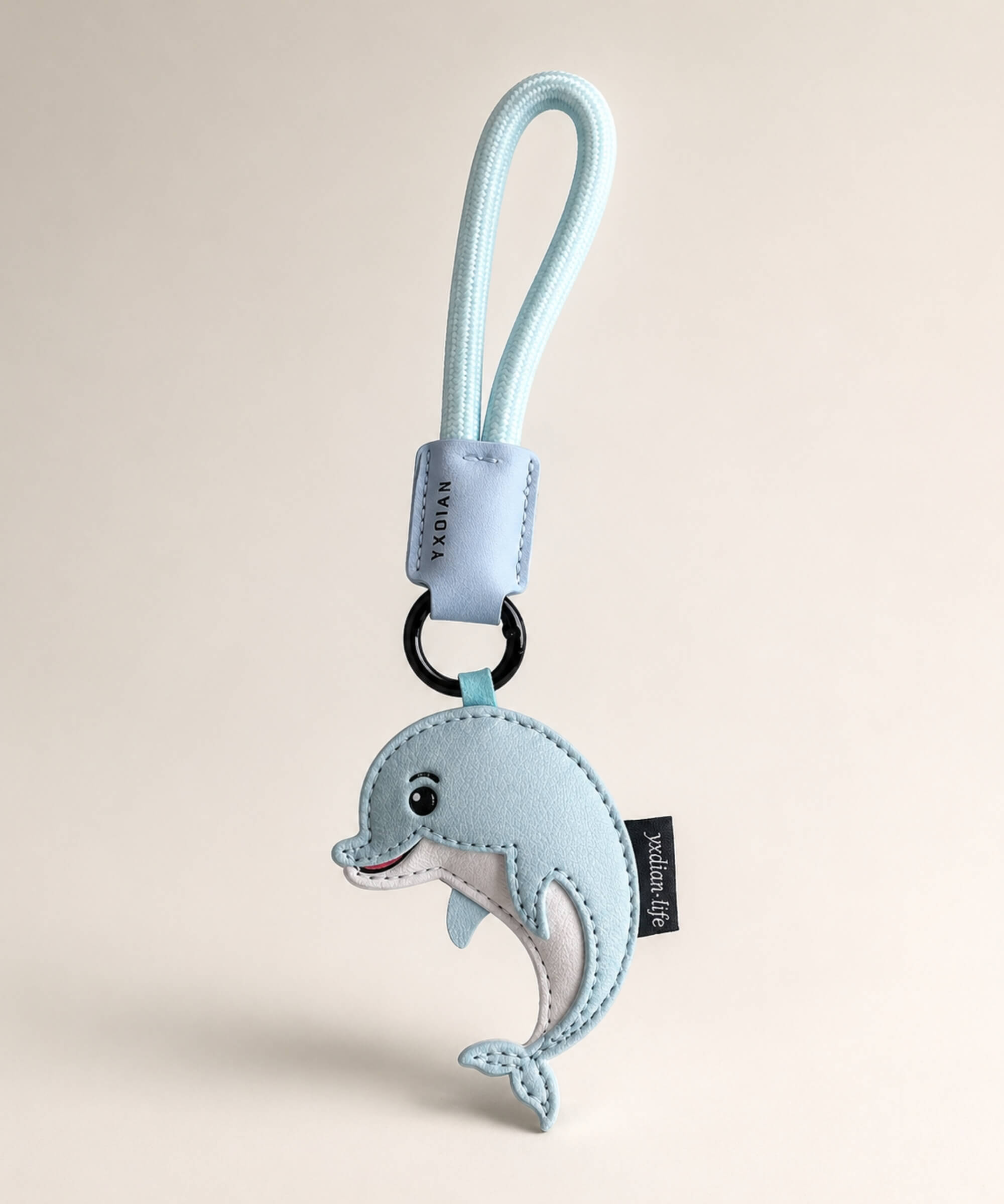 Blue cute dolphin PU leather keychain with wrist strap on a soft neutral studio background.